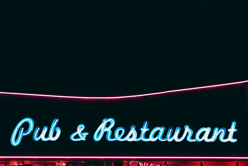 From below of vibrant pub restaurant signboard glowing with blue neon light at night